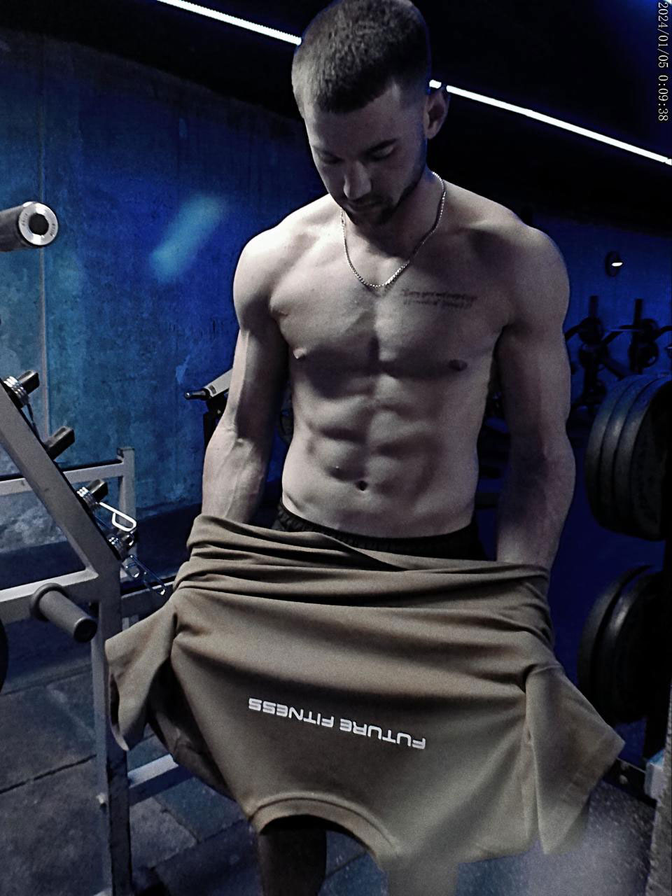 The coach is posing while taking off his t-shirt.