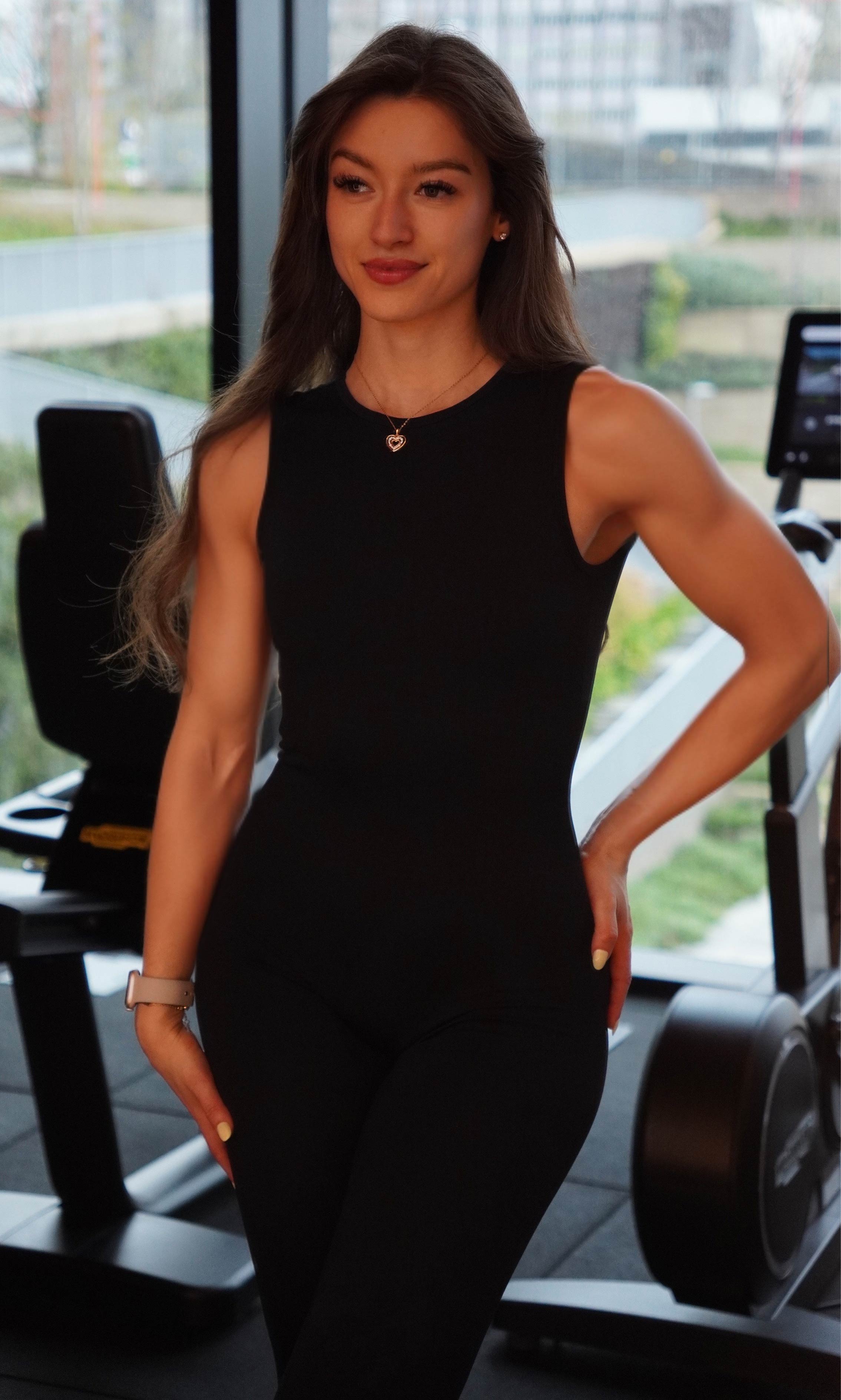 Entrenadora esta posando mientras sonrie y enseña sus abdominales definidos.