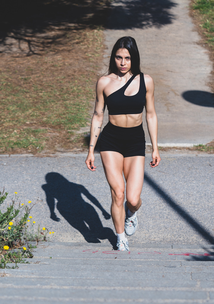 Entrenadora sentada en la calle sosteniendo su móvil.