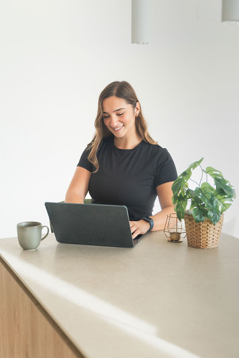 La entrenadora está sentada mientras trabaja con su computadora portátil.
