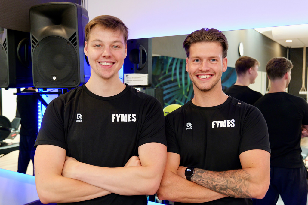 Coaches in a black t-shirts posing in front a mirror.